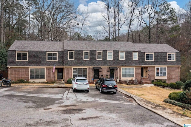 townhome / multi-family property featuring entry steps, a shingled roof, and brick siding