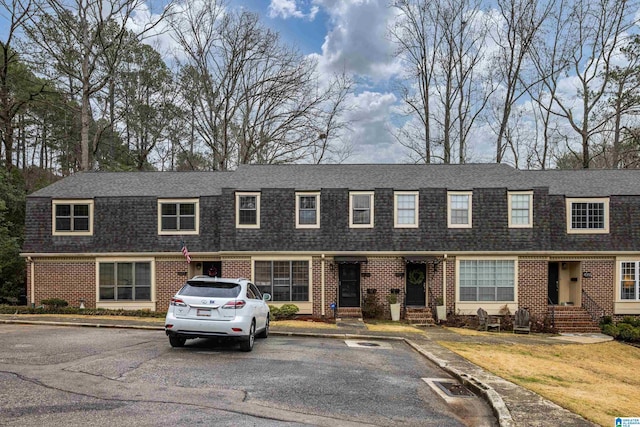 view of front of house featuring entry steps, brick siding, and a shingled roof