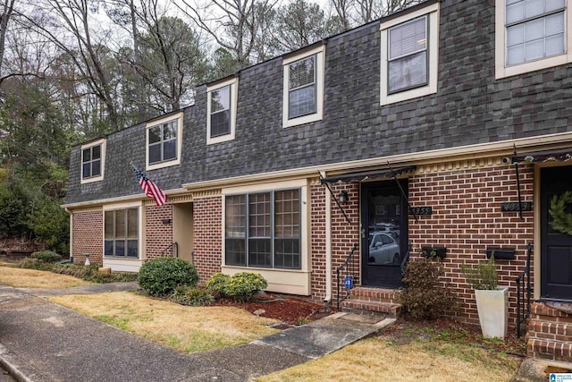 view of front of home featuring a shingled roof, entry steps, brick siding, and mansard roof