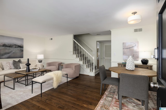 living area featuring dark wood-style floors, stairway, visible vents, and ornamental molding