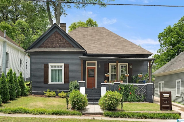 view of front of home with a front lawn, a chimney, and a porch