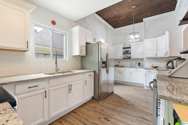 kitchen featuring light wood finished floors, open shelves, white cabinetry, a sink, and stainless steel fridge