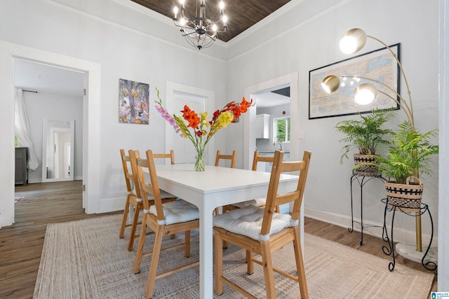 dining space featuring a chandelier, ornamental molding, baseboards, and wood finished floors