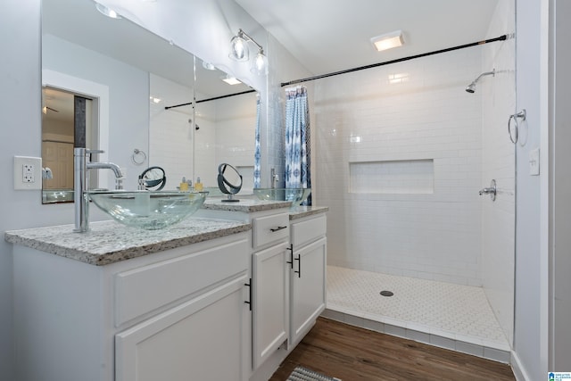 bathroom with tiled shower, wood finished floors, and vanity