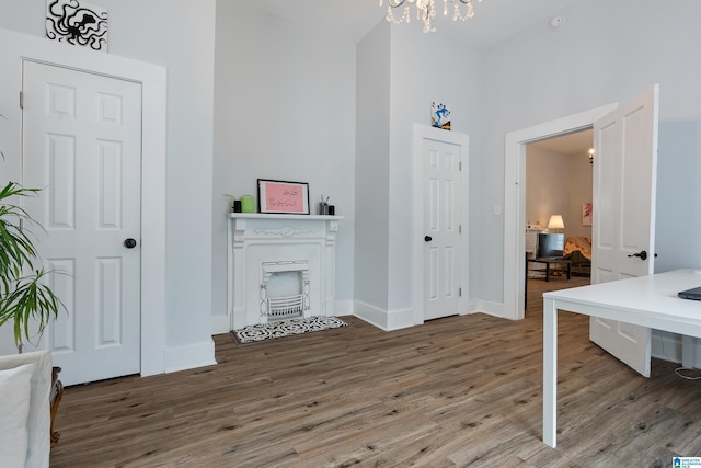 interior space featuring a notable chandelier, a towering ceiling, baseboards, and wood finished floors