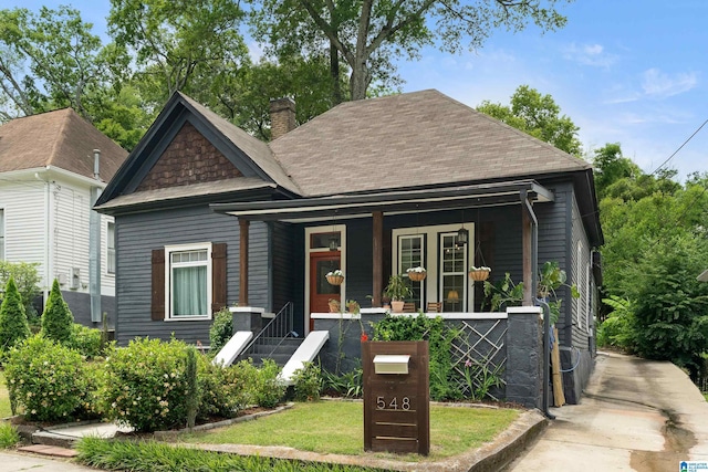 view of front of property with covered porch, a chimney, and roof with shingles