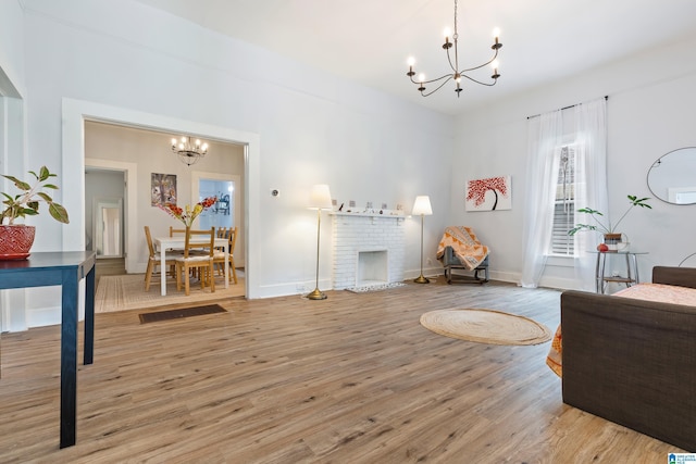 living room with a fireplace, a notable chandelier, baseboards, and wood finished floors