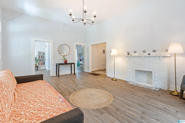 living area featuring a notable chandelier, a fireplace, baseboards, and wood finished floors