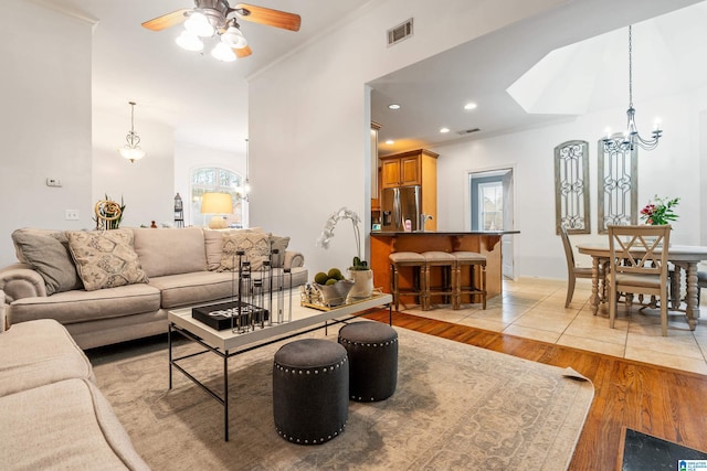 living room with light wood finished floors, plenty of natural light, visible vents, and ornamental molding