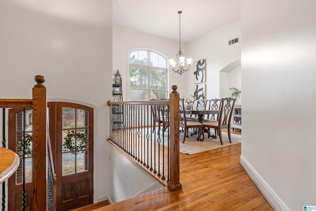 interior space featuring baseboards, visible vents, arched walkways, wood finished floors, and a chandelier