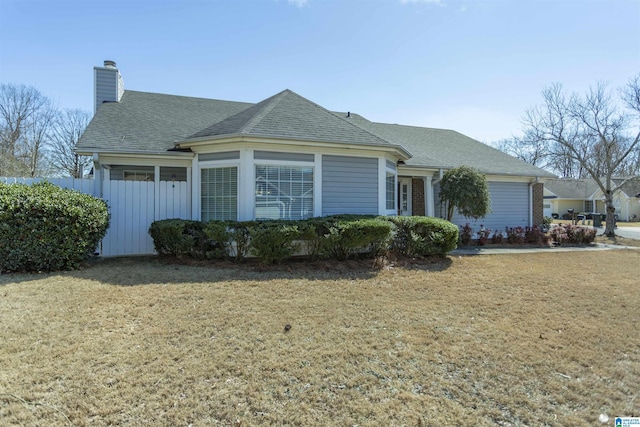 view of front of home with a shingled roof, a front yard, and a chimney