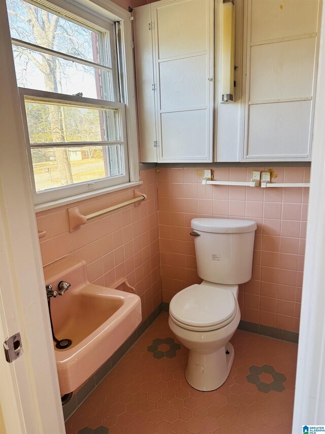 half bath with toilet and tile walls