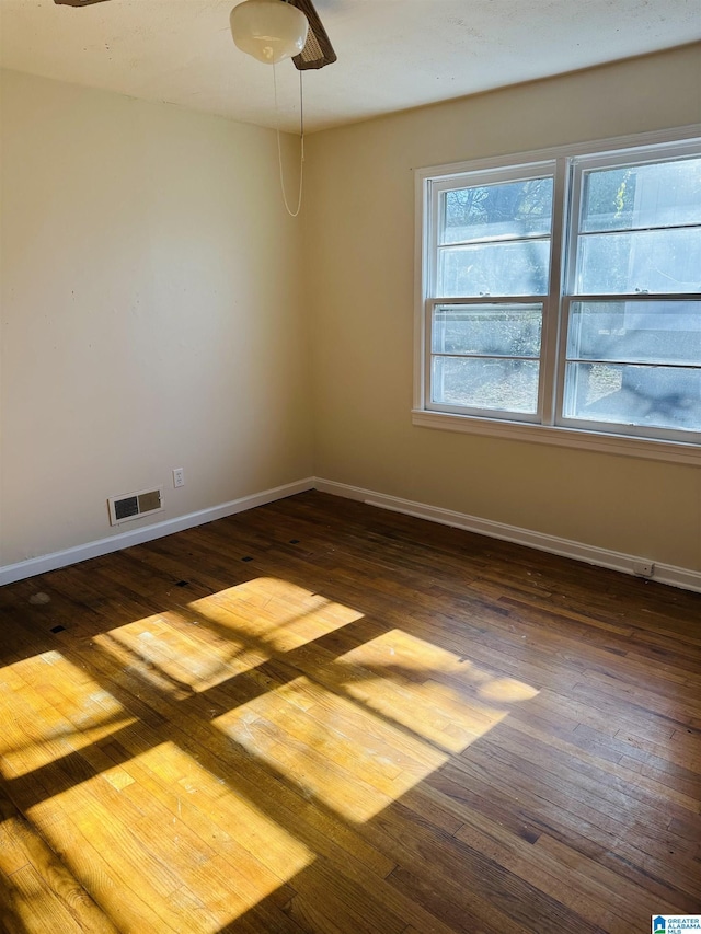 unfurnished room with baseboards, visible vents, and dark wood-style flooring