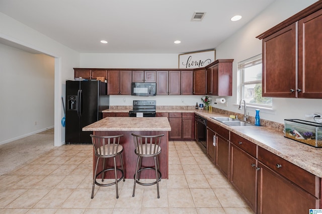 kitchen with visible vents, a kitchen island, black appliances, a sink, and light tile patterned flooring