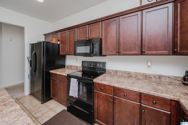 kitchen featuring light tile patterned floors, black appliances, baseboards, and light stone countertops