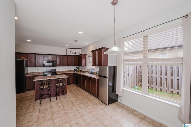 kitchen featuring a sink, hanging light fixtures, light countertops, a center island, and black appliances