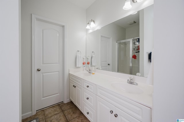 bathroom featuring double vanity, a stall shower, tile patterned flooring, and a sink