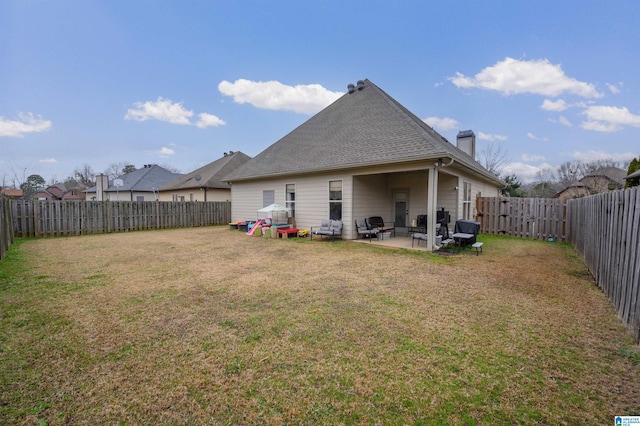 back of property featuring a patio area, a fenced backyard, a yard, and a chimney