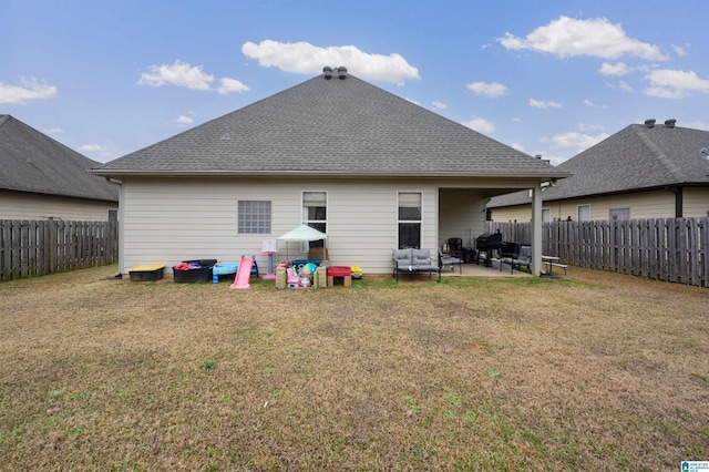 back of house featuring roof with shingles, a fenced backyard, a patio, and a lawn