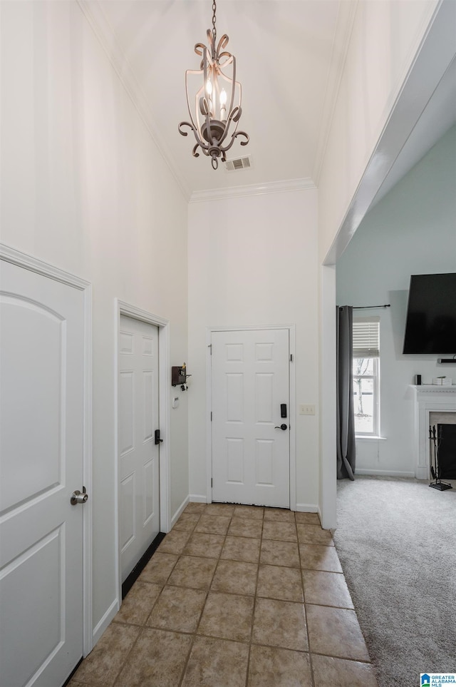 entrance foyer featuring visible vents, ornamental molding, carpet, a high ceiling, and a chandelier