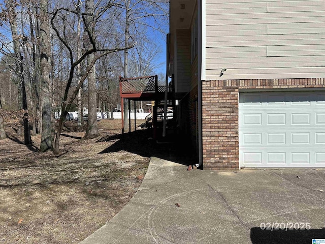 view of side of home featuring a garage and brick siding