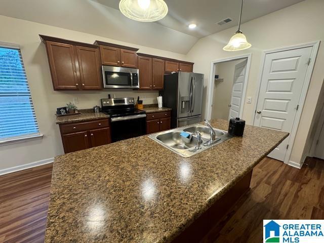 kitchen with stainless steel appliances, a sink, visible vents, vaulted ceiling, and pendant lighting