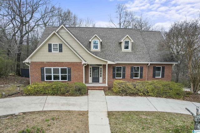 view of front of home with a shingled roof, a front lawn, and brick siding