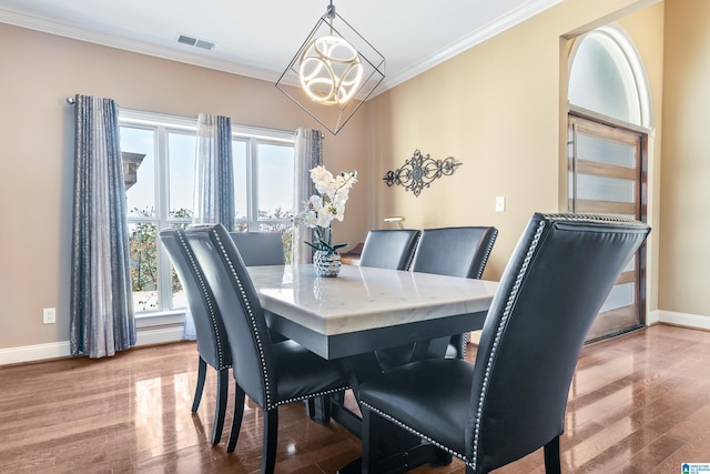 dining area with a wealth of natural light, visible vents, crown molding, and wood finished floors