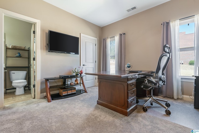 office featuring a healthy amount of sunlight, visible vents, light carpet, and baseboards