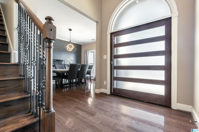 foyer entrance featuring stairs, baseboards, wood finished floors, and crown molding