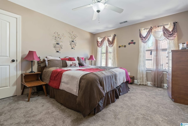 bedroom with light carpet, ceiling fan, visible vents, and baseboards