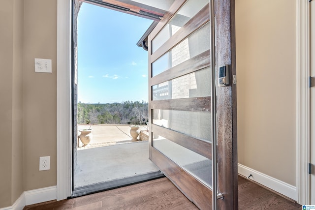 doorway to outside featuring baseboards and wood finished floors