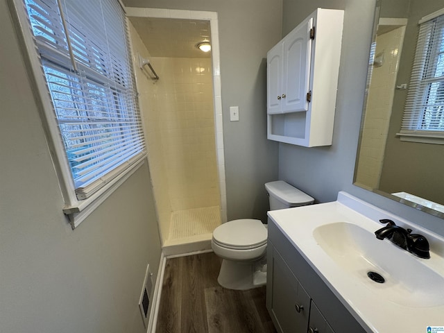 bathroom featuring toilet, a stall shower, plenty of natural light, and wood finished floors