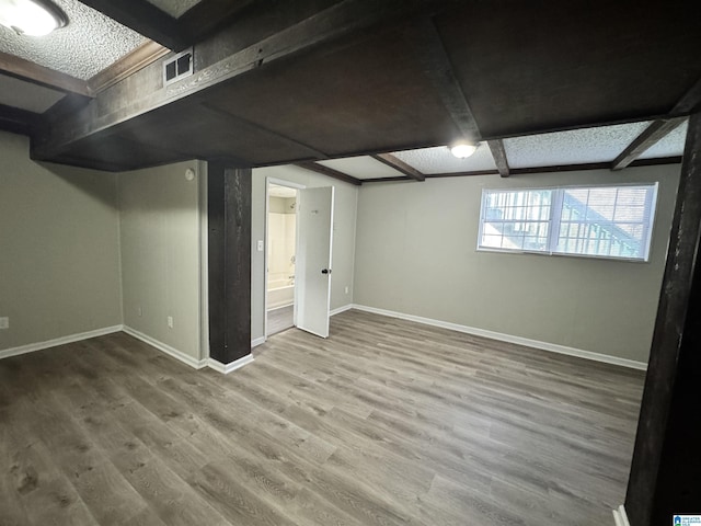 below grade area with baseboards, visible vents, and wood finished floors