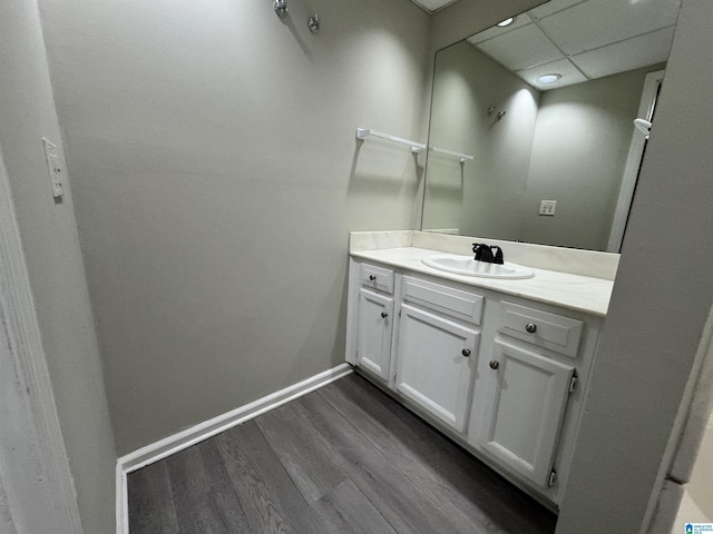 bathroom featuring vanity, wood finished floors, a paneled ceiling, and baseboards