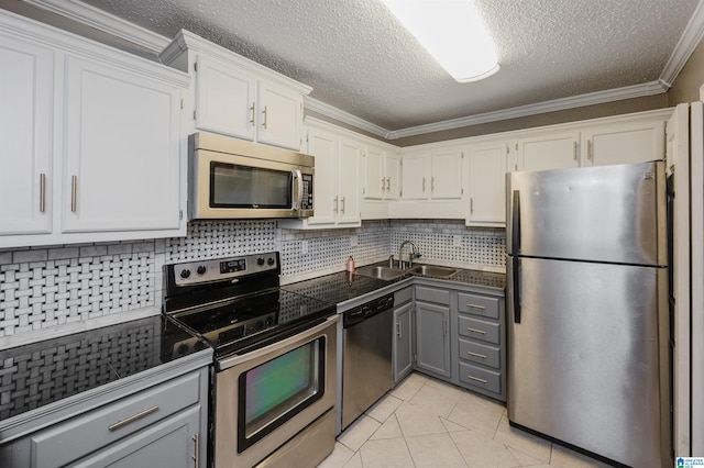 kitchen featuring light tile patterned floors, white cabinets, ornamental molding, gray cabinets, and stainless steel appliances