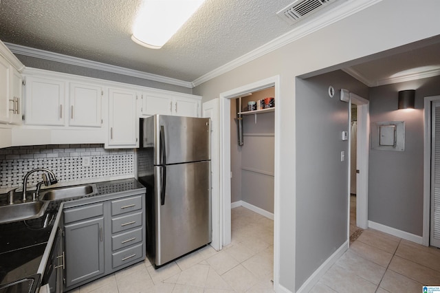 kitchen featuring dark countertops, gray cabinetry, white cabinets, and freestanding refrigerator