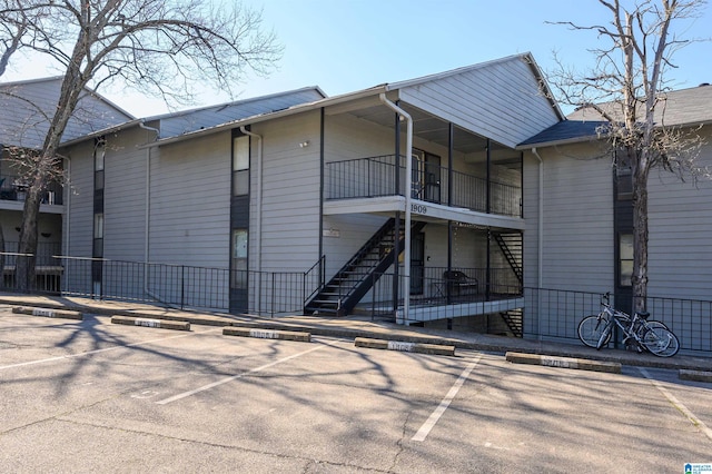 view of property with uncovered parking, fence, and stairway