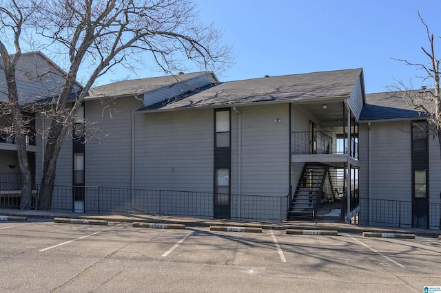 view of building exterior featuring uncovered parking, fence, and stairs