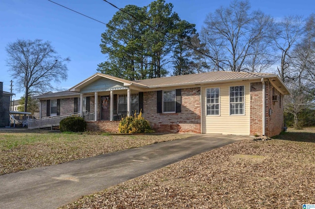 ranch-style house with covered porch, metal roof, and brick siding