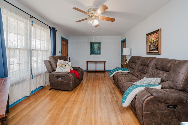 living area with a ceiling fan, baseboards, and wood finished floors