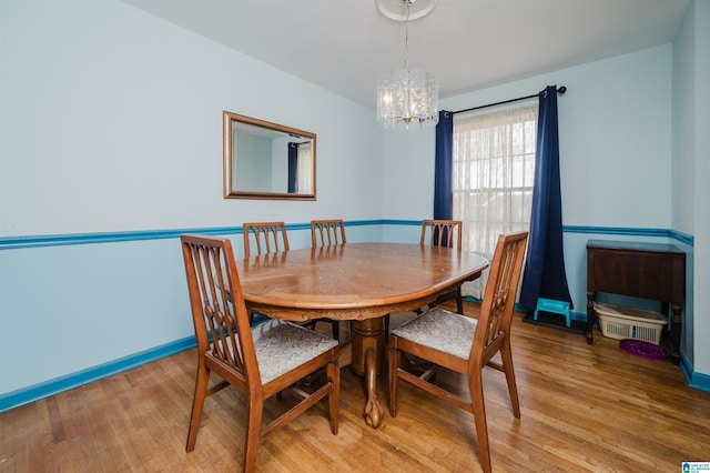 dining room with a chandelier, baseboards, and light wood finished floors