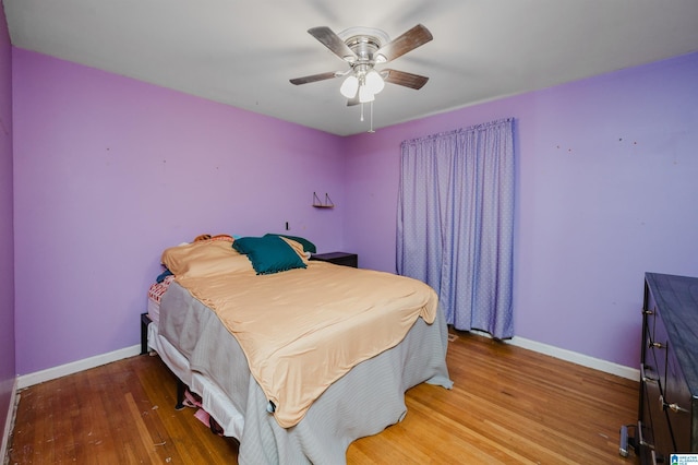 bedroom featuring ceiling fan, baseboards, and wood finished floors