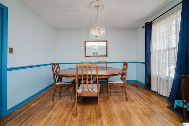 dining room with a chandelier, light wood-style flooring, and baseboards