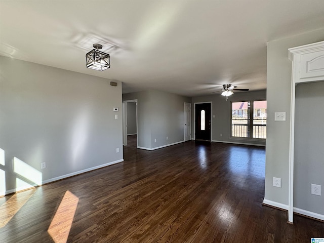 unfurnished living room with dark wood-style floors, ceiling fan, and baseboards