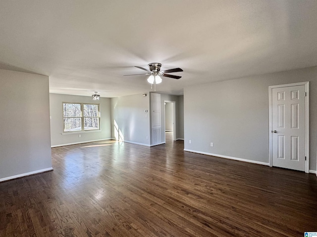 spare room featuring dark wood-type flooring, a ceiling fan, and baseboards