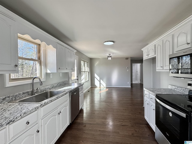 kitchen with white cabinets, dark wood-style floors, light stone countertops, stainless steel appliances, and a sink