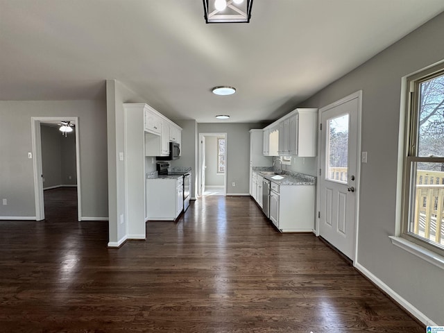 kitchen with stainless steel appliances, light stone counters, dark wood-type flooring, and white cabinets