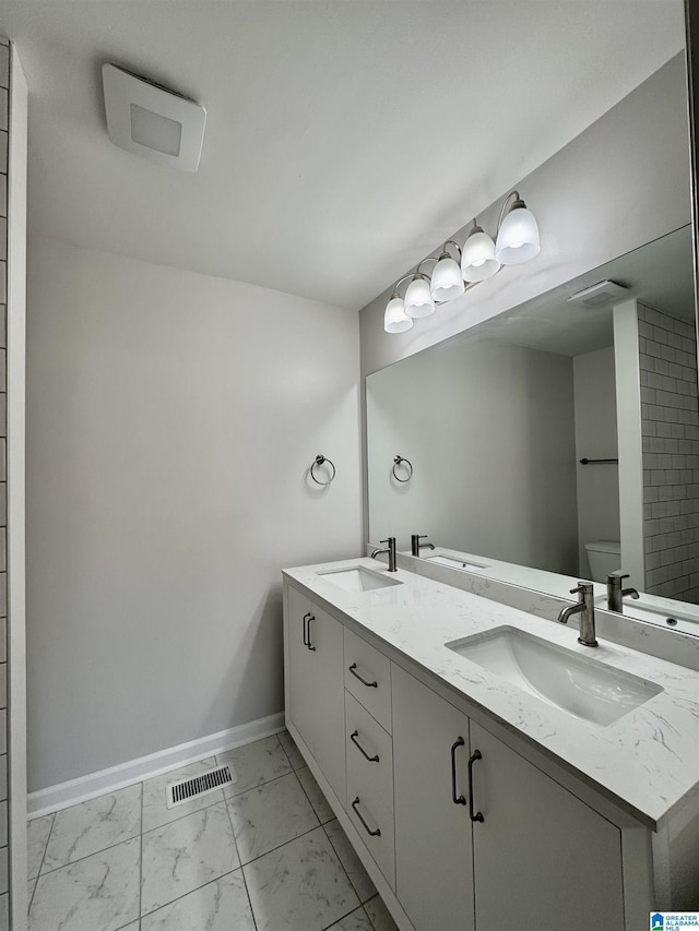 bathroom featuring marble finish floor, baseboards, a sink, and toilet