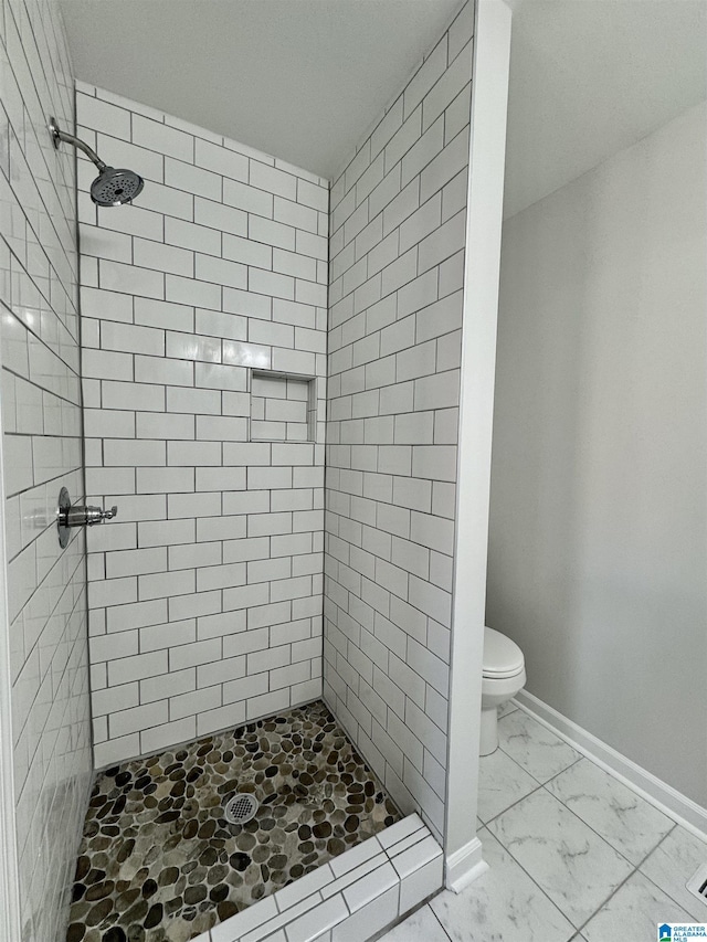 bathroom with marble finish floor, a stall shower, toilet, and baseboards